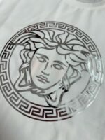 ⁦تيشيرت فيرساتشي الجديد بياقة دائرية وأكمام قصيرة، يحمل شعار العلامة التجارية الكلاسيكي على المقدمة.⁩ - الصورة ⁦7⁩